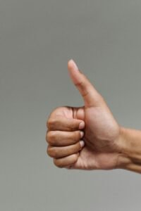 A close-up of a hand showing a thumbs up gesture, symbolizing success and approval.